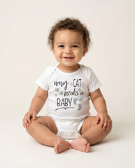 Baby wearing a white onesie with text sitting on a light background