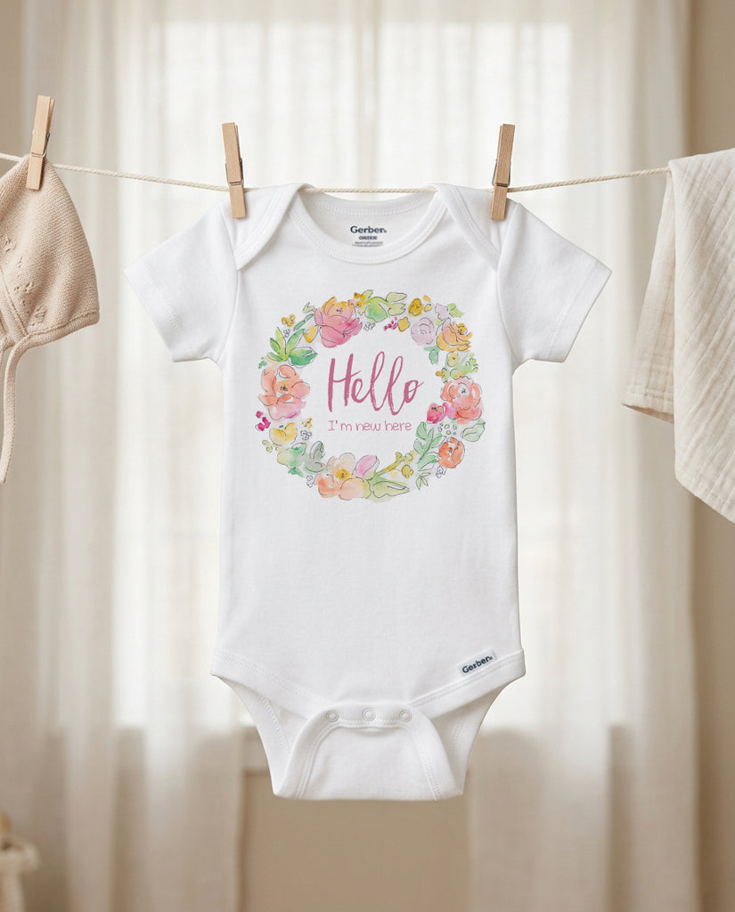 Baby onesie with floral design and text hanging on a clothesline.