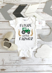 May include: White baby onesie with the text 'FUTURE LITTLE FARMER' in black and a green tractor graphic. The onesie has three white snaps at the bottom.