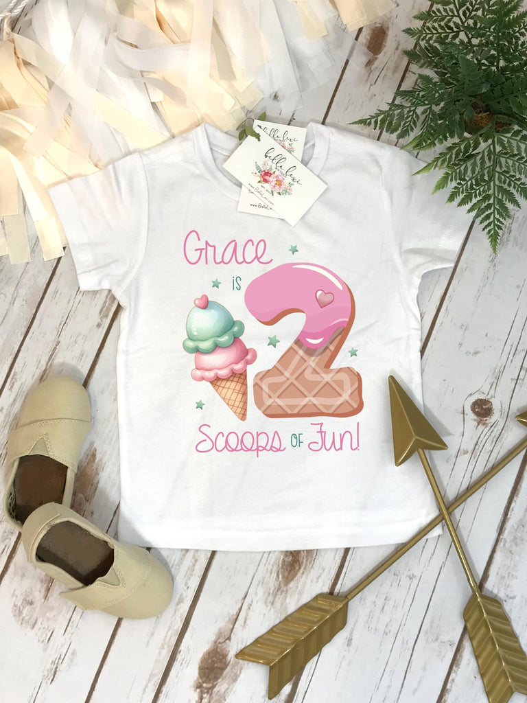 May include: White t-shirt with a pink and white ice cream cone and a pink donut with a pink heart on top. The text "Grace is 2 Scoops of Fun!" is printed on the shirt.