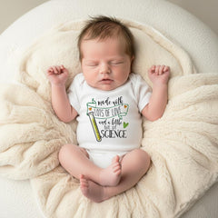 May include: A white short-sleeved baby bodysuit featuring a green banner with the text "made with LOTS OF LOVE and a little bit of SCIENCE" and a graphic of a yellow test tube. The garment is made of soft fabric and has a simple crew neckline.