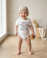 May include: A white short-sleeved bodysuit featuring the black text: I NEVER DREAMED OF HAVING A Super Cool AUNT but there she is KILLIN' IT. The garment is worn with a beige ribbed knit beanie and is accompanied by a small wooden toy vehicle.