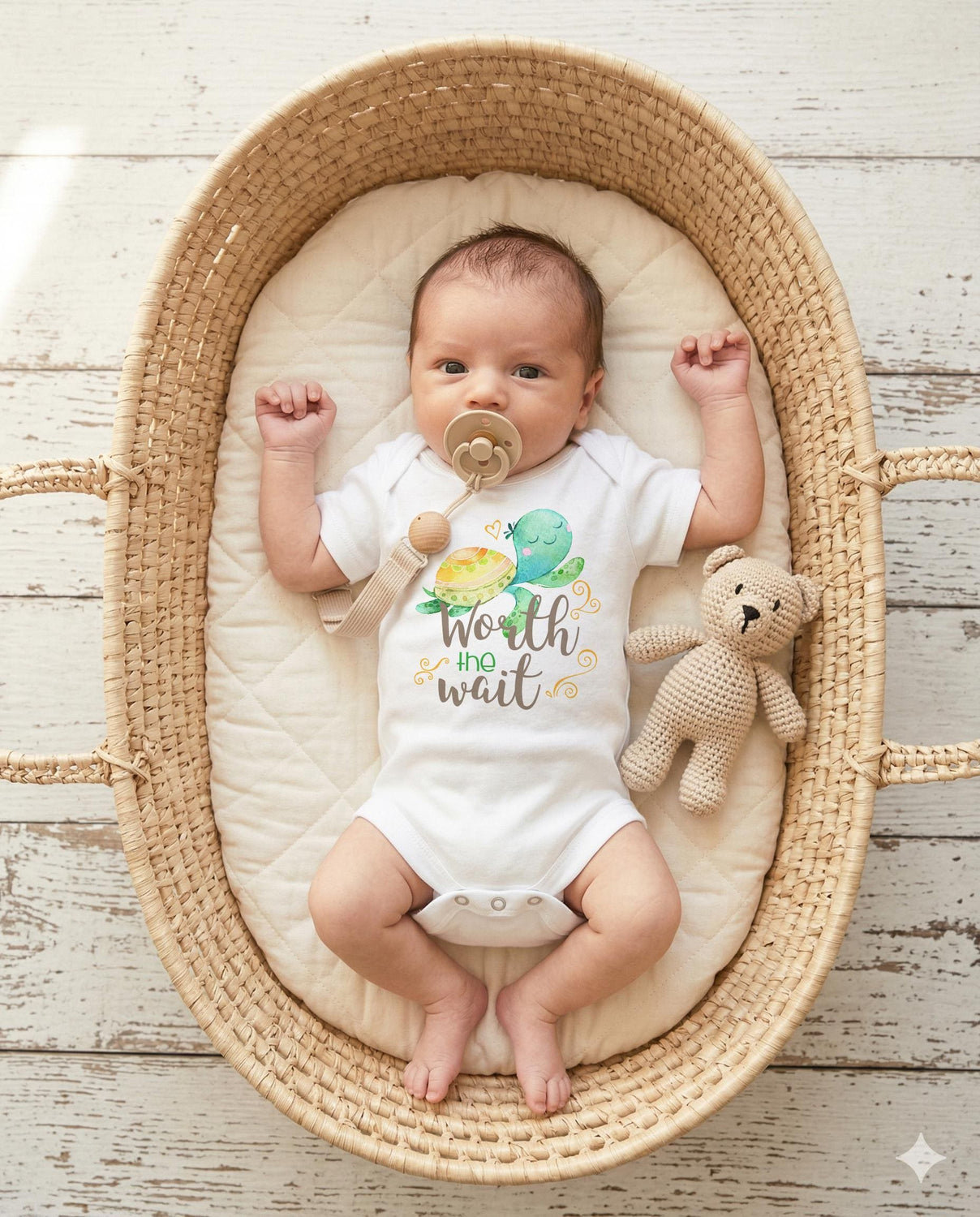 May include: A white baby bodysuit featuring a watercolor illustration of a green sea turtle and the text Worth the wait in brown and green script. The bodysuit is worn by a baby with a beige pacifier and a small crocheted tan teddy bear.