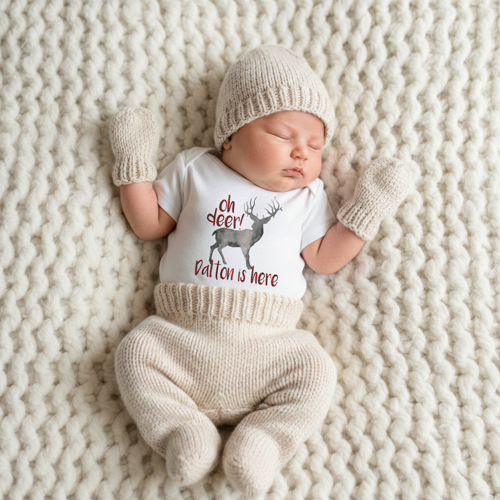 Newborn baby in a matching outfit with text and graphics on a textured blanket